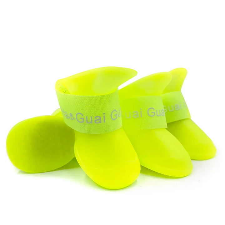 Pets-Shop. Four neon yellow silicone dog shoes with "Guai Guai" printed on the strap, against a white background. Shopets-Amazon.