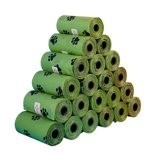 Pets-Shop: Multiple rolls of green dog waste bags with paw print designs, stacked in a pyramid shape. Shopets-Amazon.